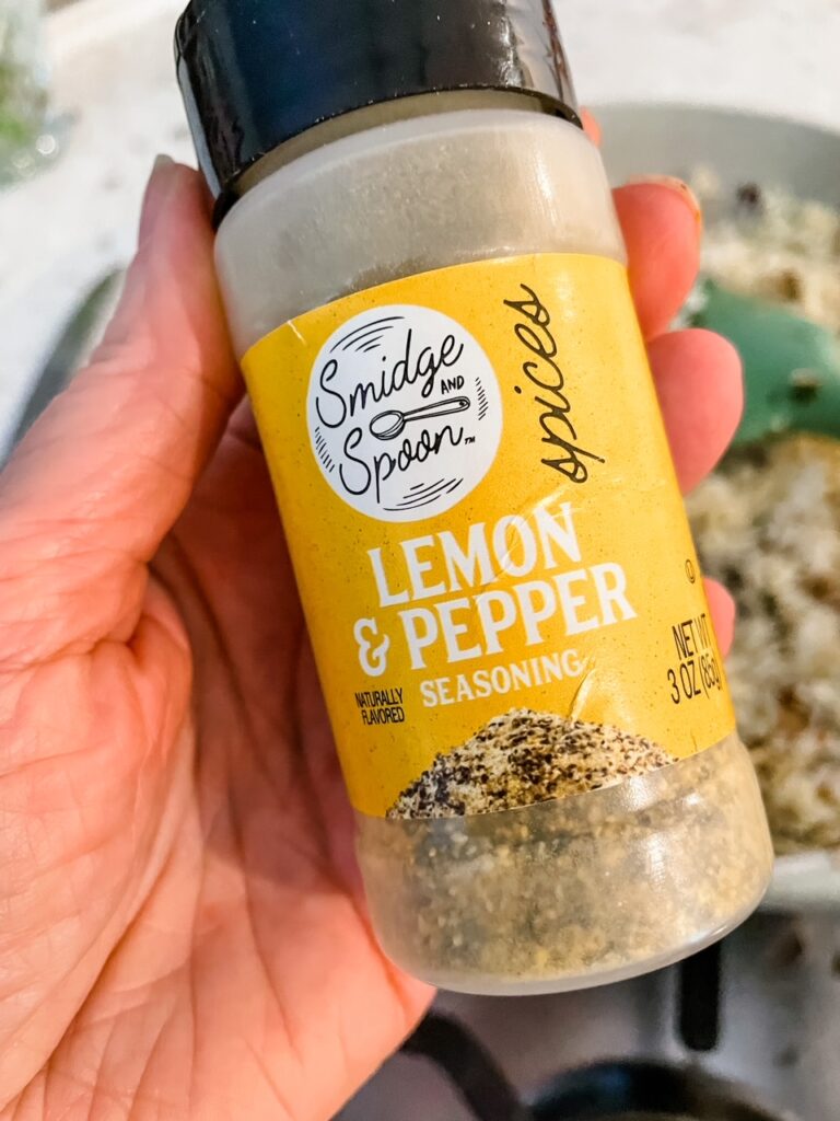 A hand holding up the lemon pepper seasoning