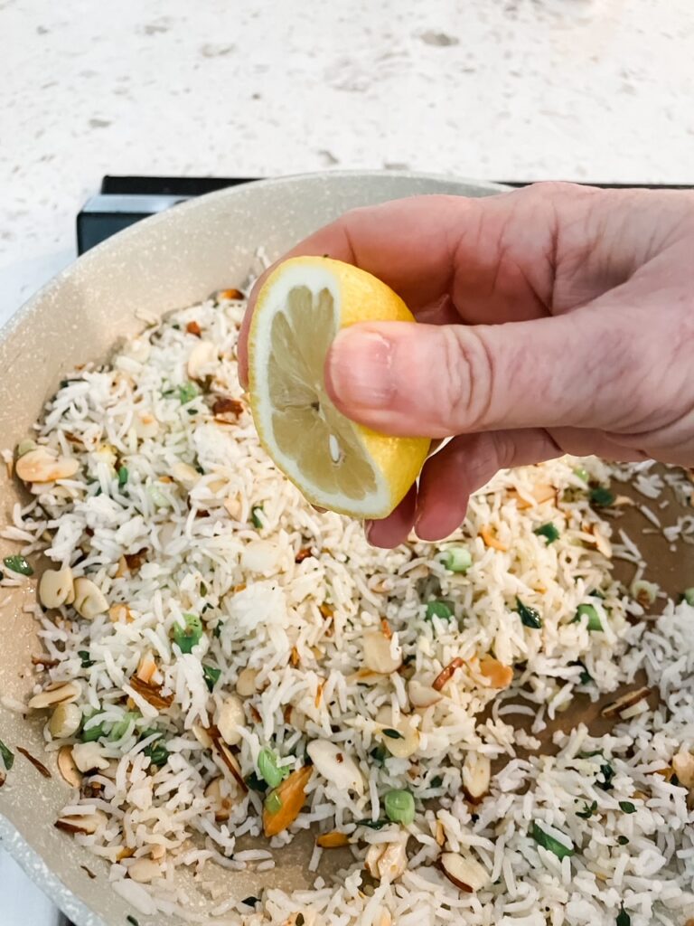 A lemon slice being squeezed over the  Lemon Herb Rice Pilaf 
