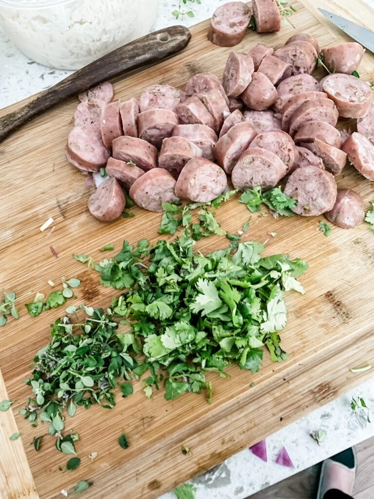 Sliced Chicken Sausage and herbs on a cutting board