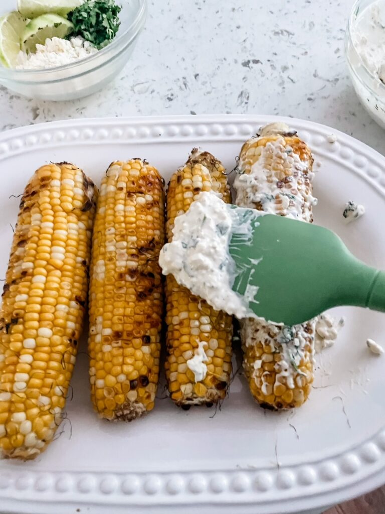 The sauce being brushed onto the grilled corn