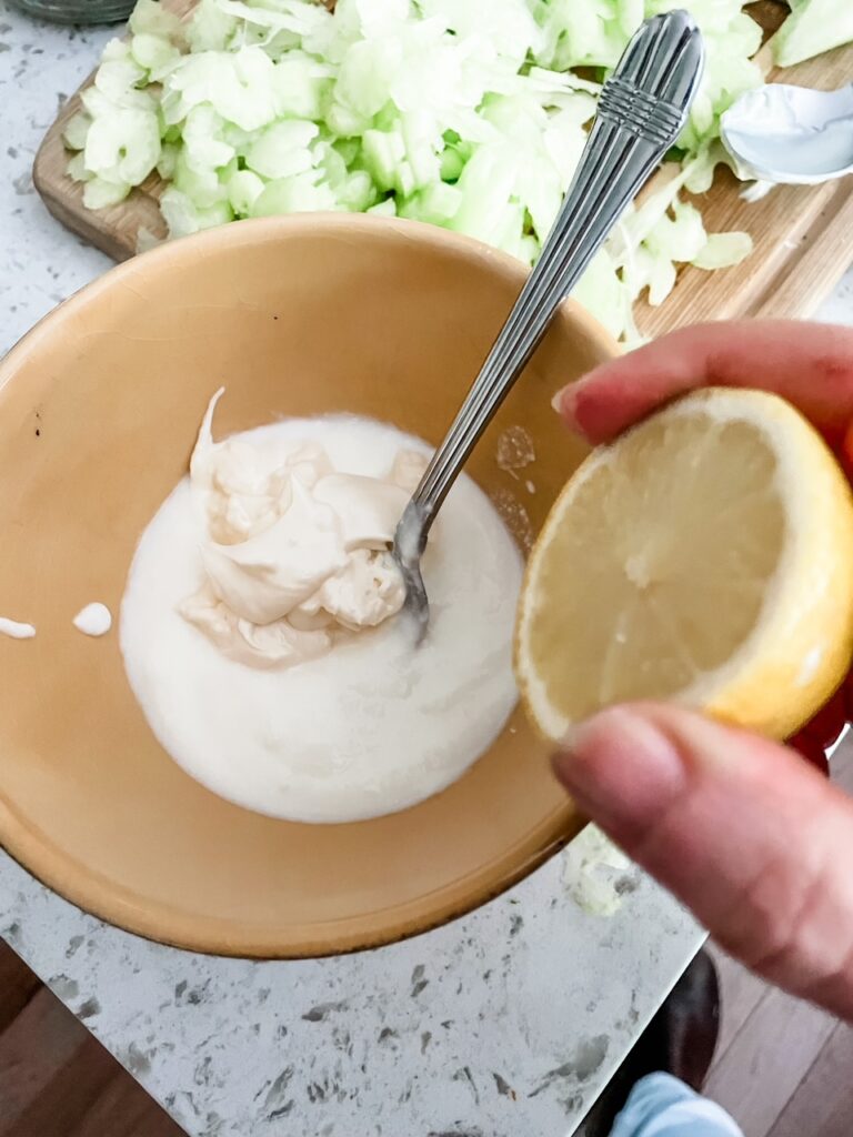 The lemon being squeezed into a bowl containing yogurt for the dressing