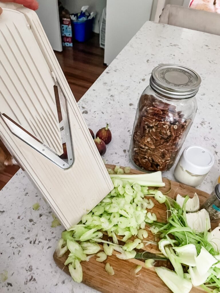 The celery being sliced on a mandolin