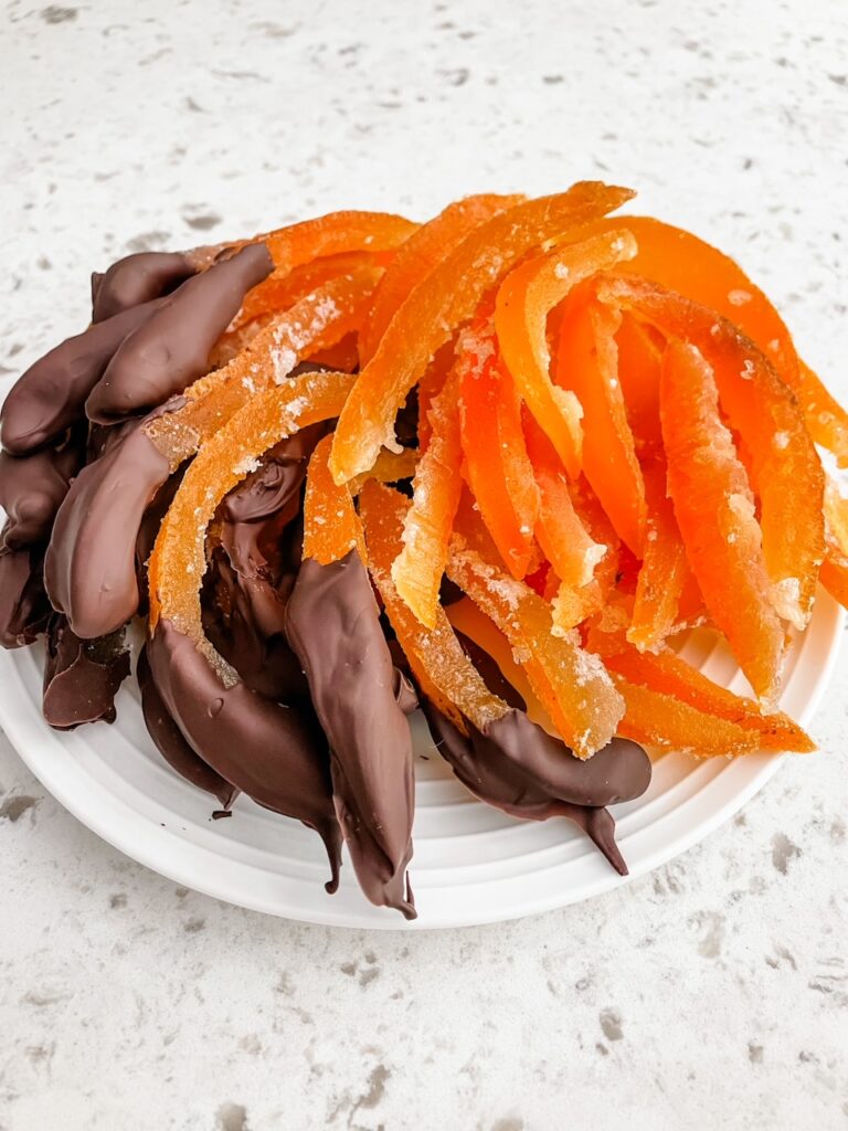 The finished Easy Candied Grapefruit Peel on a plate, with half dipped in chocolate