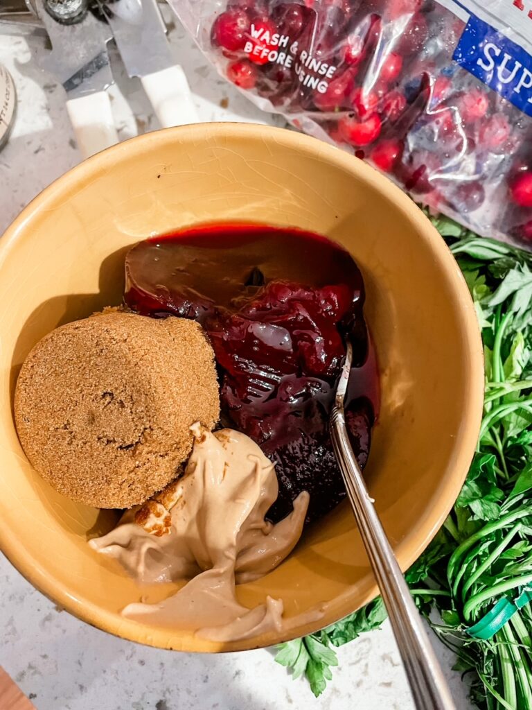 The three sauce ingredients (brown sugar, dijon mustard, and cranberry sauce) in a bowl