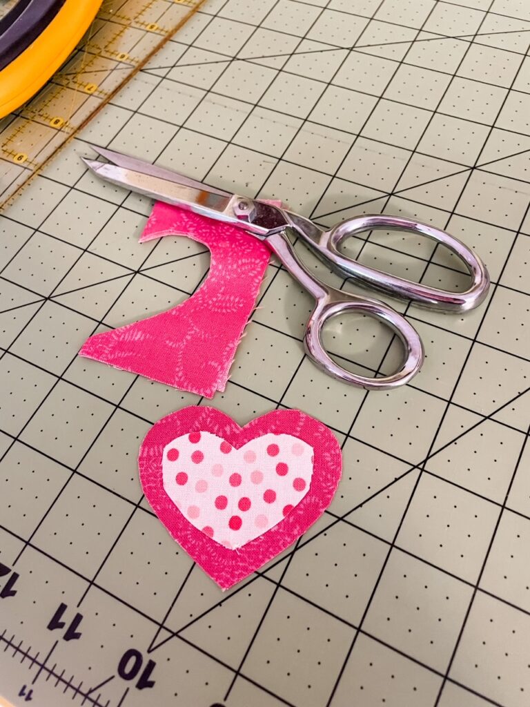 An example of two hearts being cut from fabric scraps