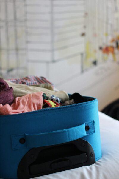 A suitcase partially packed and placed on a bed, showing 'pack light', one of Marie's airport survival tips