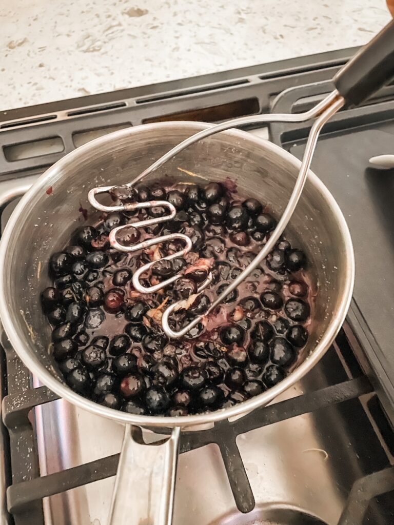 The blueberries being smashed in the heavy bottom pan