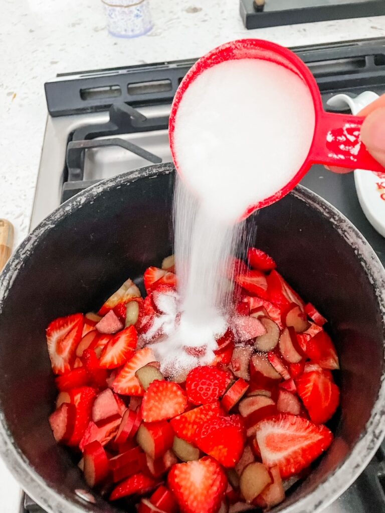 Sugar being poured into the fruit mixture