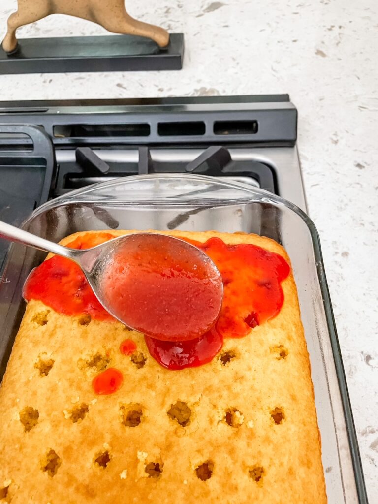 The filling for the Strawberry Rhubarb Poke Cake being spooned over