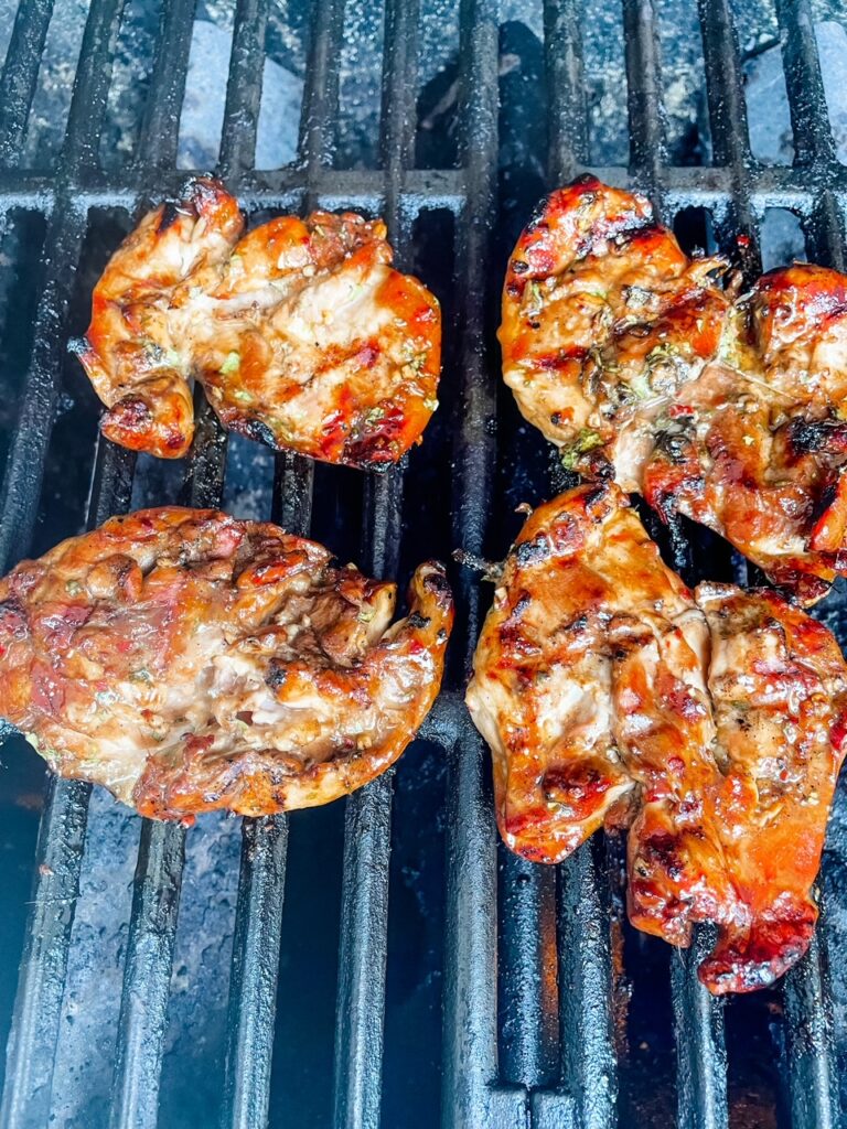 The marinated chicken grilling on a grill