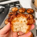 One of the finished Pineapple Orange Muffins being held up with a bite taken from it