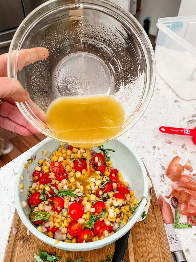 The vinaigrette being poured into the Fresh Corn and Cherry Tomato Salad