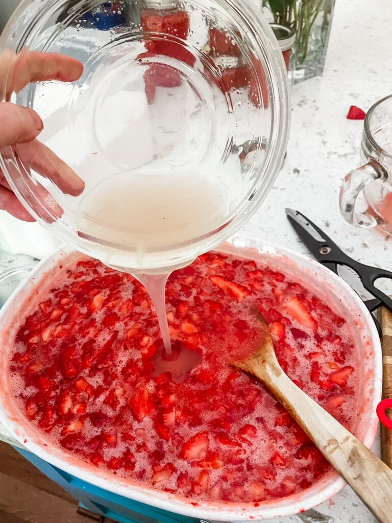 The pectin and lemon mixture being poured into the strawberries