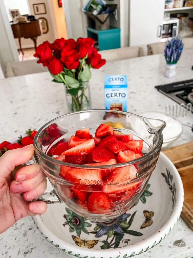 A measuring cup full of fresh strawberry slices