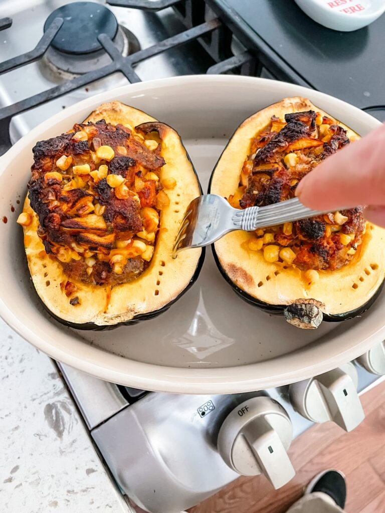 A fork making cuts into the squash prior to placing it in the oven