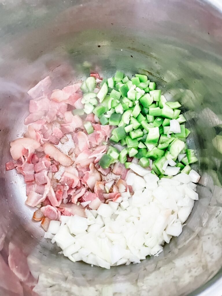 The chopped bacon, onion, and pepper in a pan