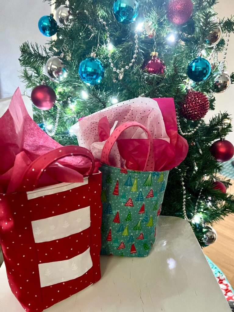 The finished DIY Fabric Gift Bags for Christmas in front of a Christmas tree