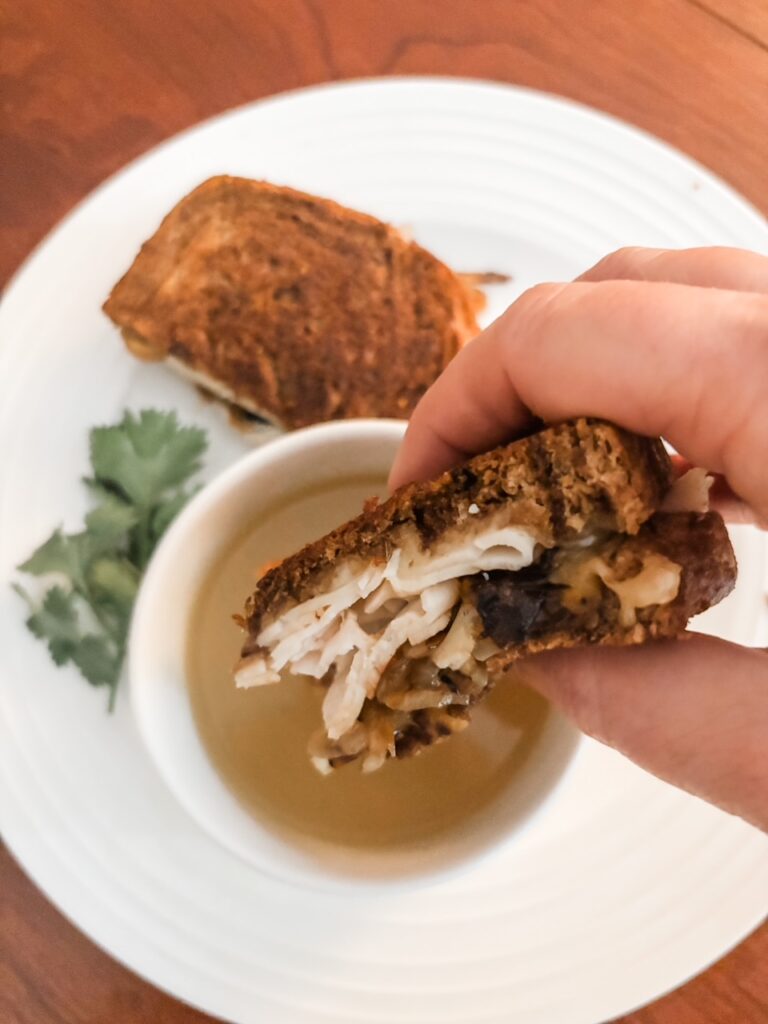 Marie dipping a the Chicken French Dip Sandwich