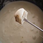 A skewer dipping a cubed bread piece into the Homemade Cheese Fondue