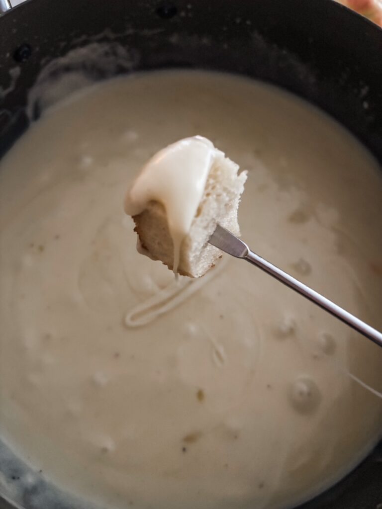 A skewer dipping a cubed bread piece into the Homemade Cheese Fondue