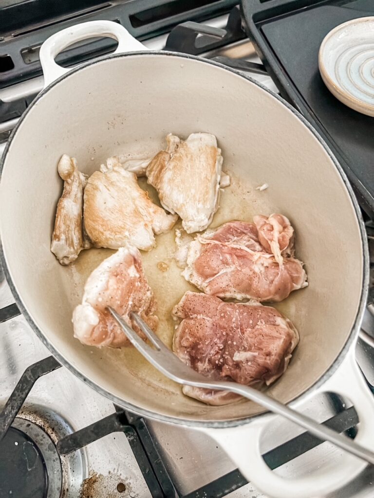 The chicken thighs being seared