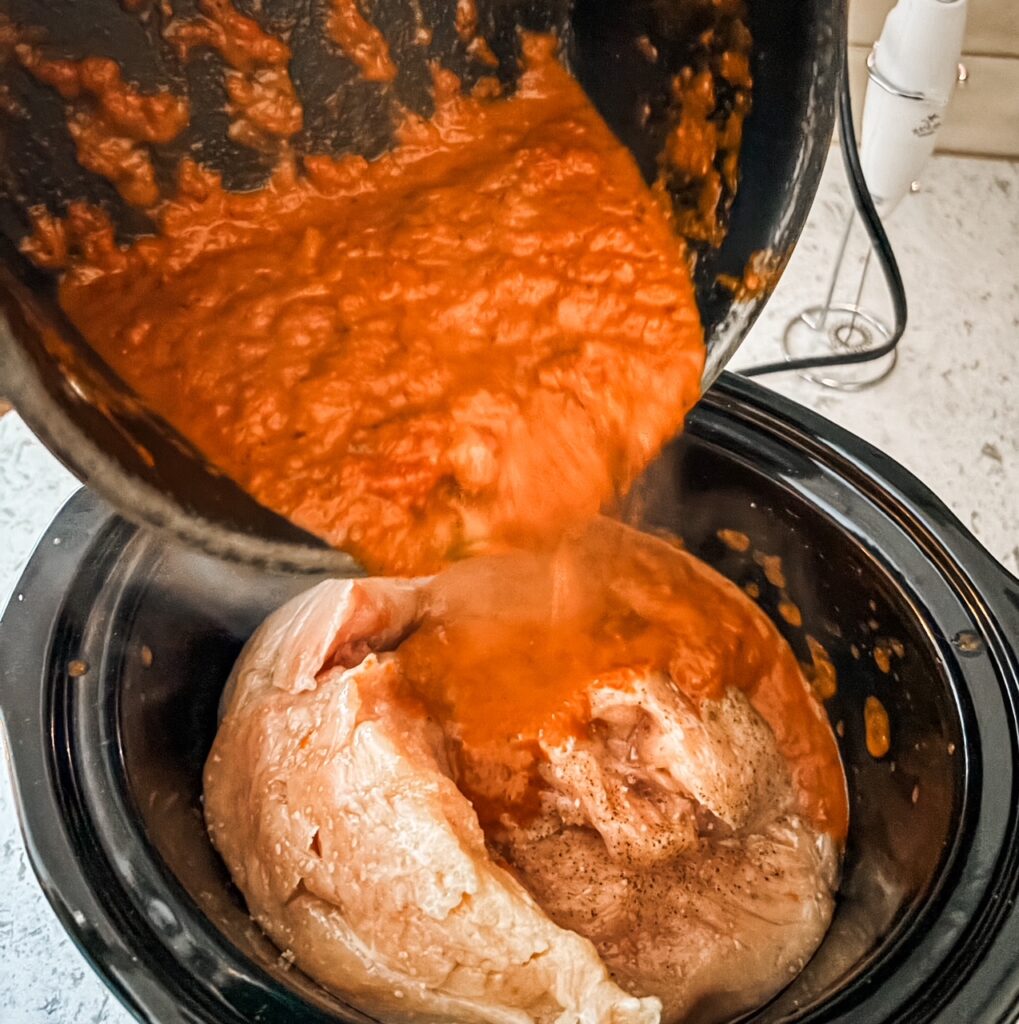 The sauce being poured on the cooked chicken