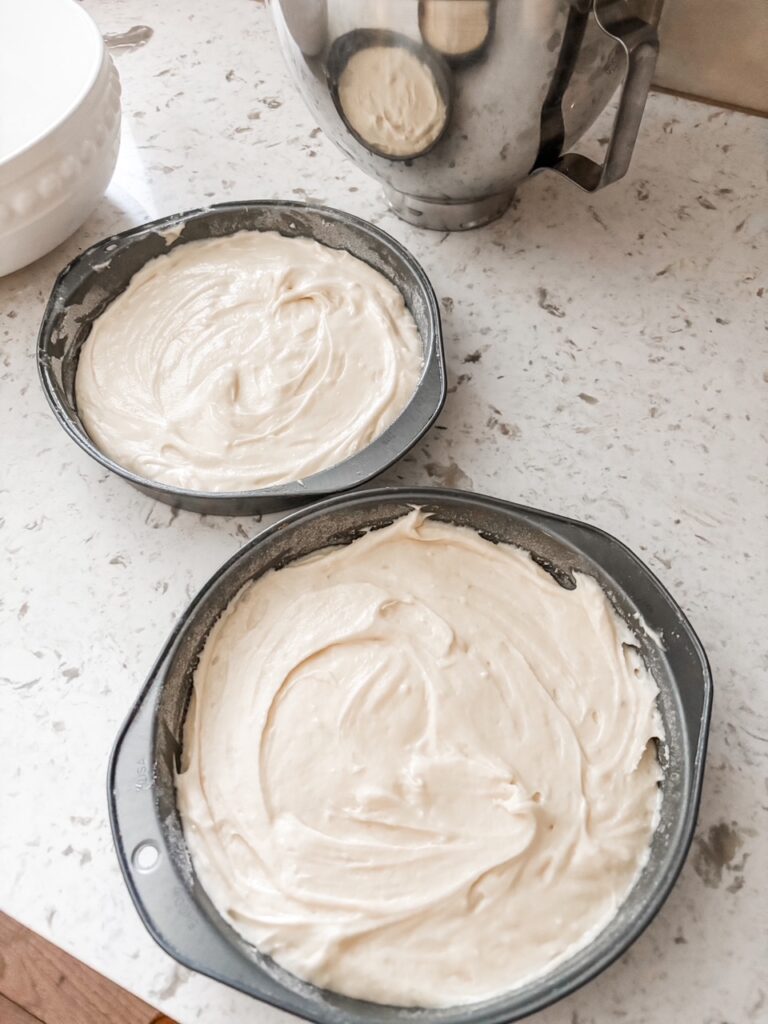Two pans filled with the cake batter sitting on a counter