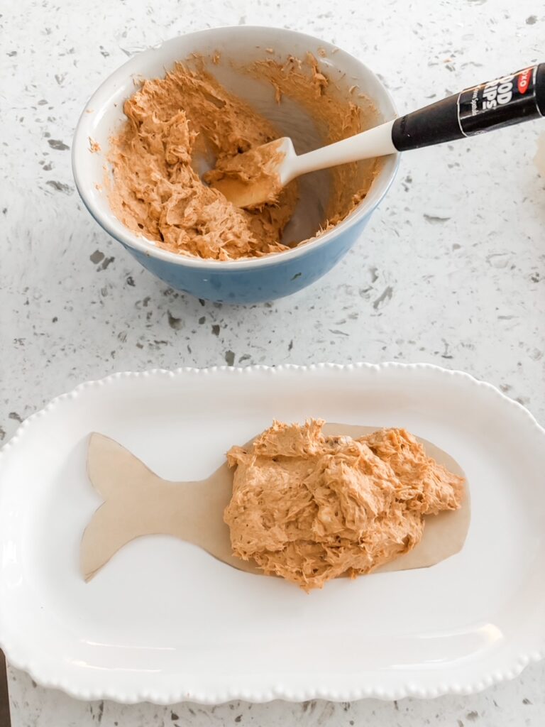 The fish shape cut out on parchment with a dab of the spread on it