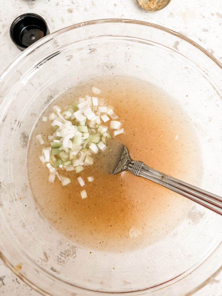 The green onion being added to the dressing mixture