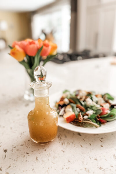 The Maple Vinaigrette Dressing in a bottle next to a plate of salad