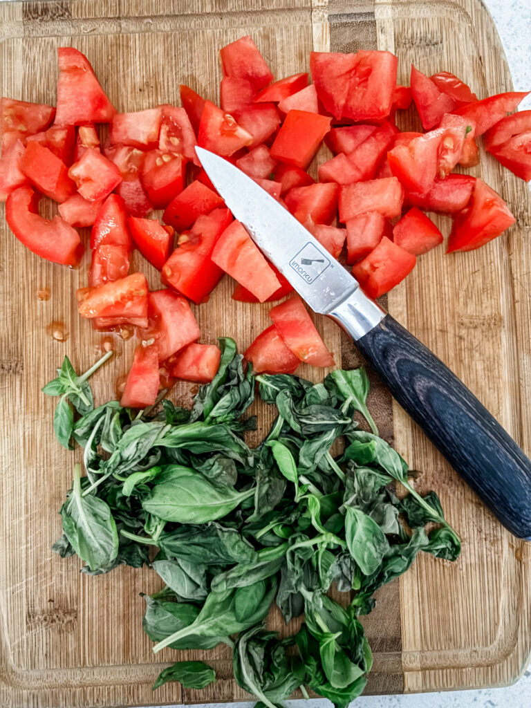 Diced tomatoes and basil on a wooden cutting board
