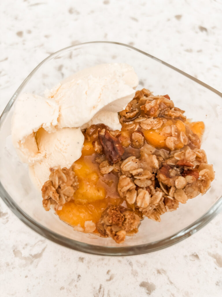 The finished Gluten-Free Peach Crumble Dessert in a serving bowl with ice cream