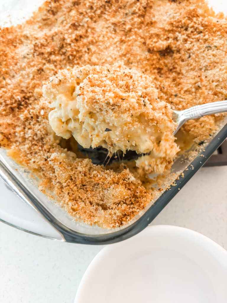 The Butternut Squash Mac and Cheese with Sage in a baking dish with a scoop being taken out