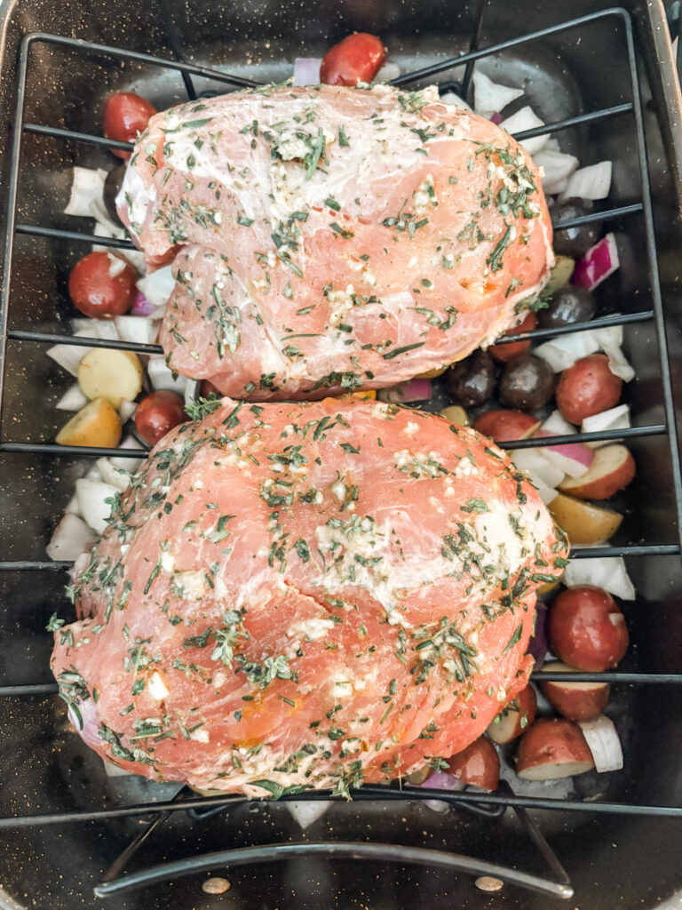 The herb rubbed pork on a roasting rack with the vegetables underneath
