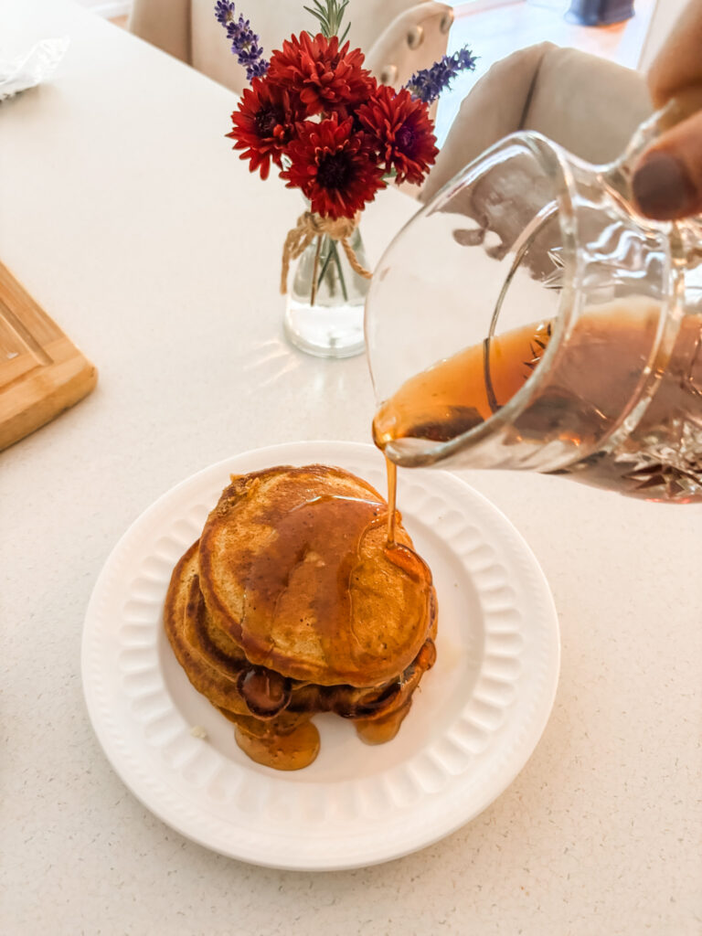 Marie pouring syrup on top of the Pumpkin Spice Pancakes