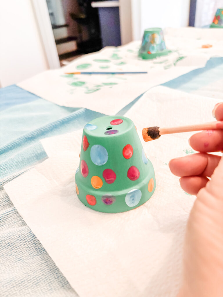 Marie using a stipple brush to paint ornaments