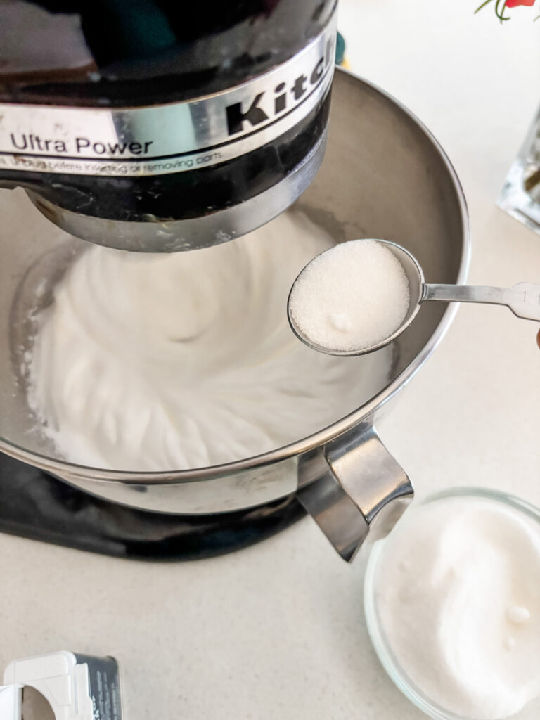 The sugar being added to the egg whites in the stand mixer