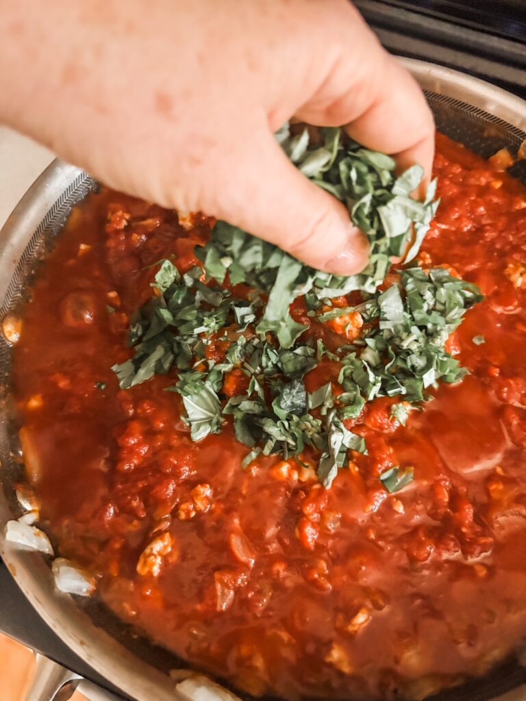The fresh basil being added to the sauce