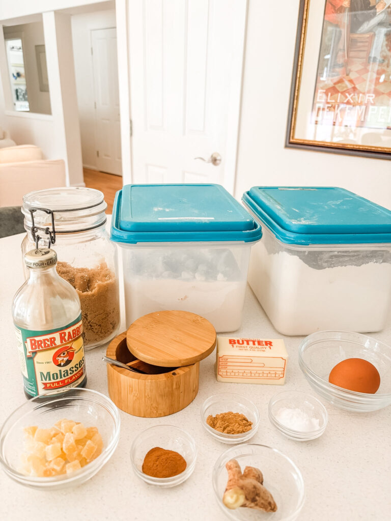 Ingredients for triple ginger molasses cookies laid out on a kitchen counter, including Brer Rabbit molasses, butter, brown sugar, flour, an egg, crystallized ginger, fresh ginger root, cinnamon, and ground ginger