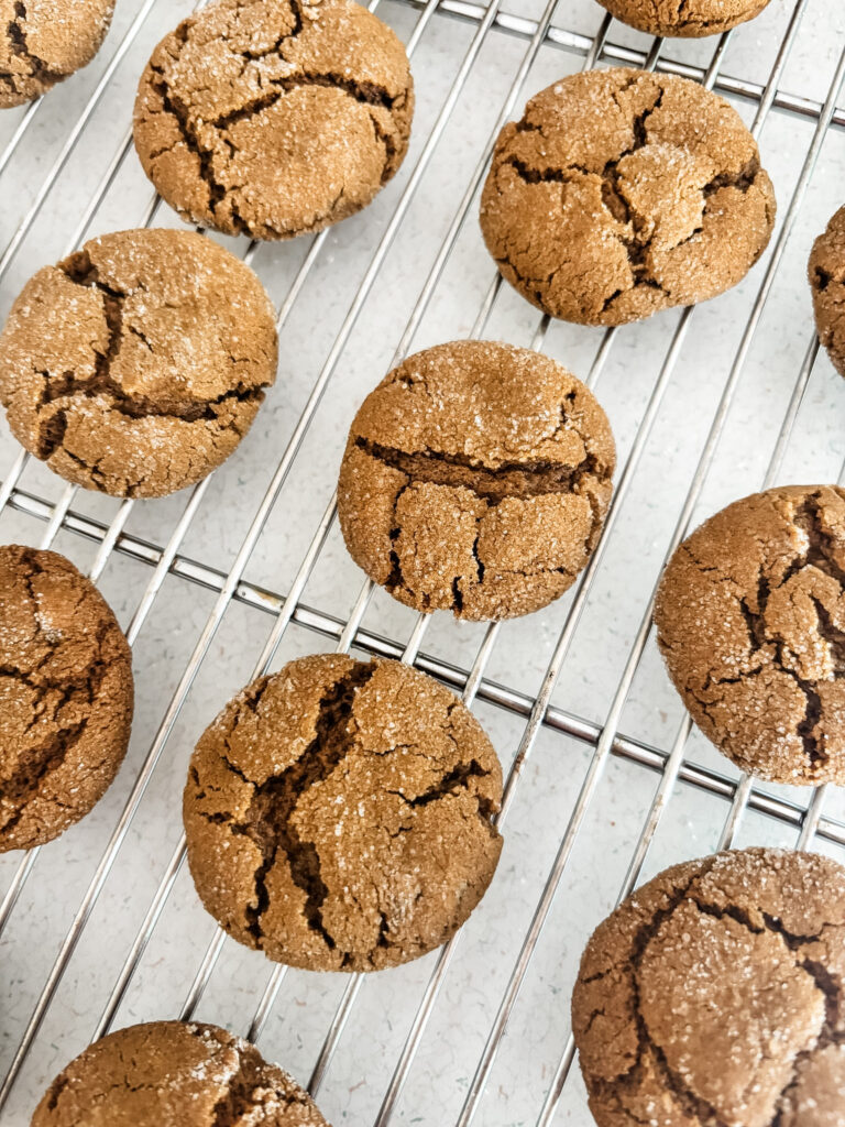 Sugar-coated triple ginger molasses cookies cooling on a wire rack, showing their characteristic crinkled, cracked tops