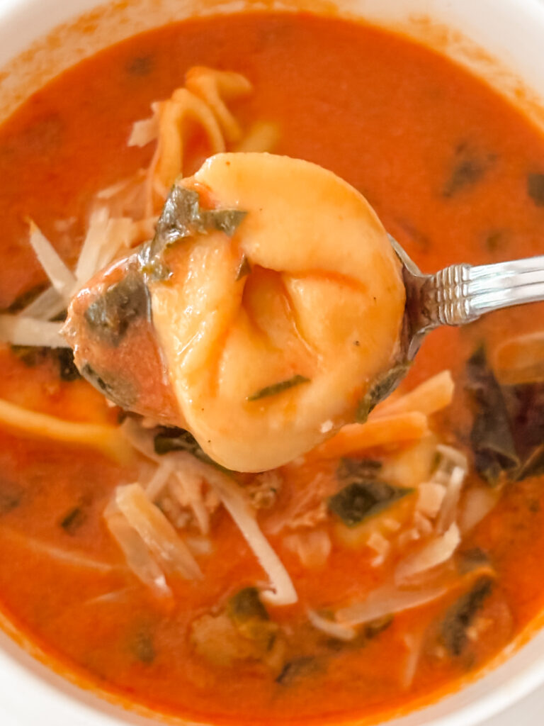 A close up spoonful of the finished creamy tomato tortellini 