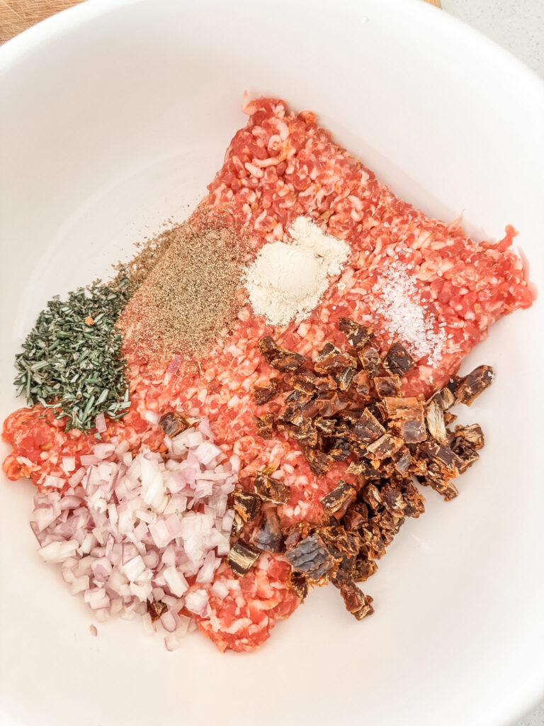 The spices and medjool dates with the ground sausage, prior to mixing