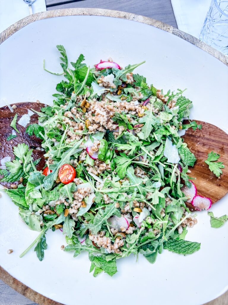 Charlie Bird Salad with farro, shaved parmesan, pistachios, cherry tomatoes, and thinly sliced radishes over arugula and herbs