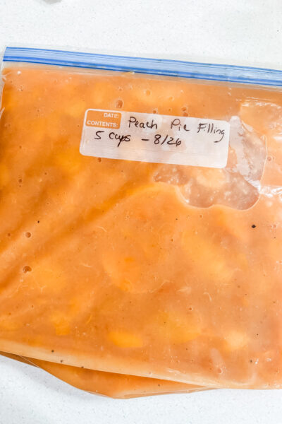 Sealed freezer bags of peach pie filling labeled with the date, laid flat for storage