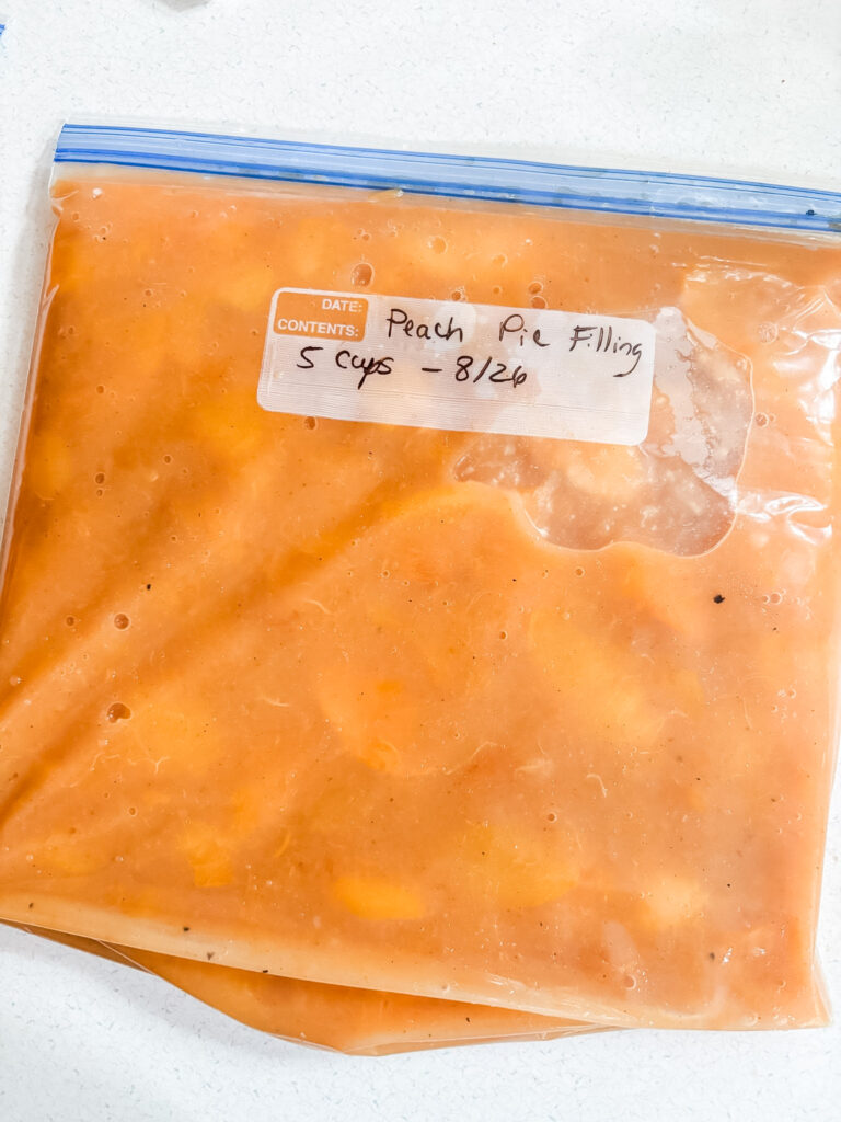 Sealed freezer bags of peach pie filling labeled with the date, laid flat for storage