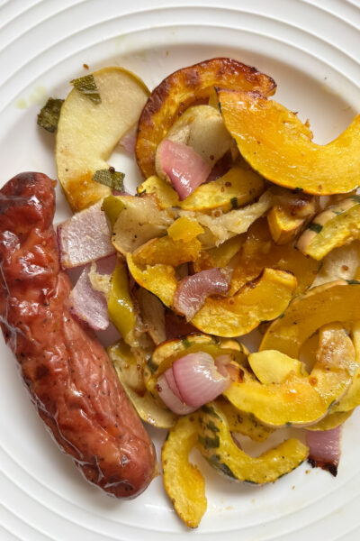 Delicata squash and chicken sausage sheet pan dinner with roasted squash half-moons, red onion, apple, sage, and browned sausages