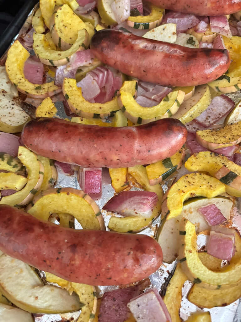 Roasted delicata squash sheet pan dinner fresh from the oven with caramelized edges and browned sausage