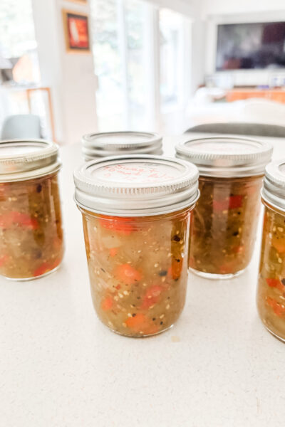 Jars of homemade green tomato sweet relish with diced green tomatoes and red bell peppers