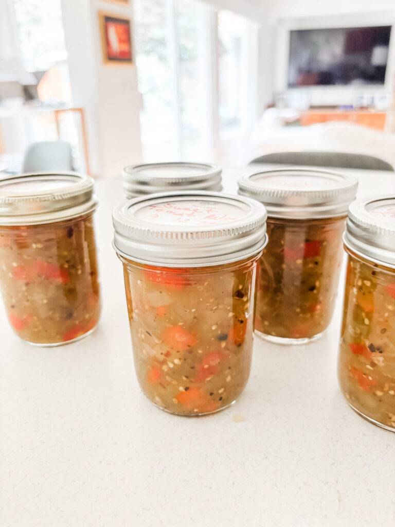 Jars of homemade green tomato sweet relish with diced green tomatoes and red bell peppers