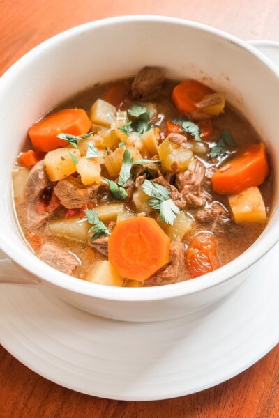 A bowl of healthy beef and beer stew with lean beef, potatoes, carrots, and celery in a rich savory broth